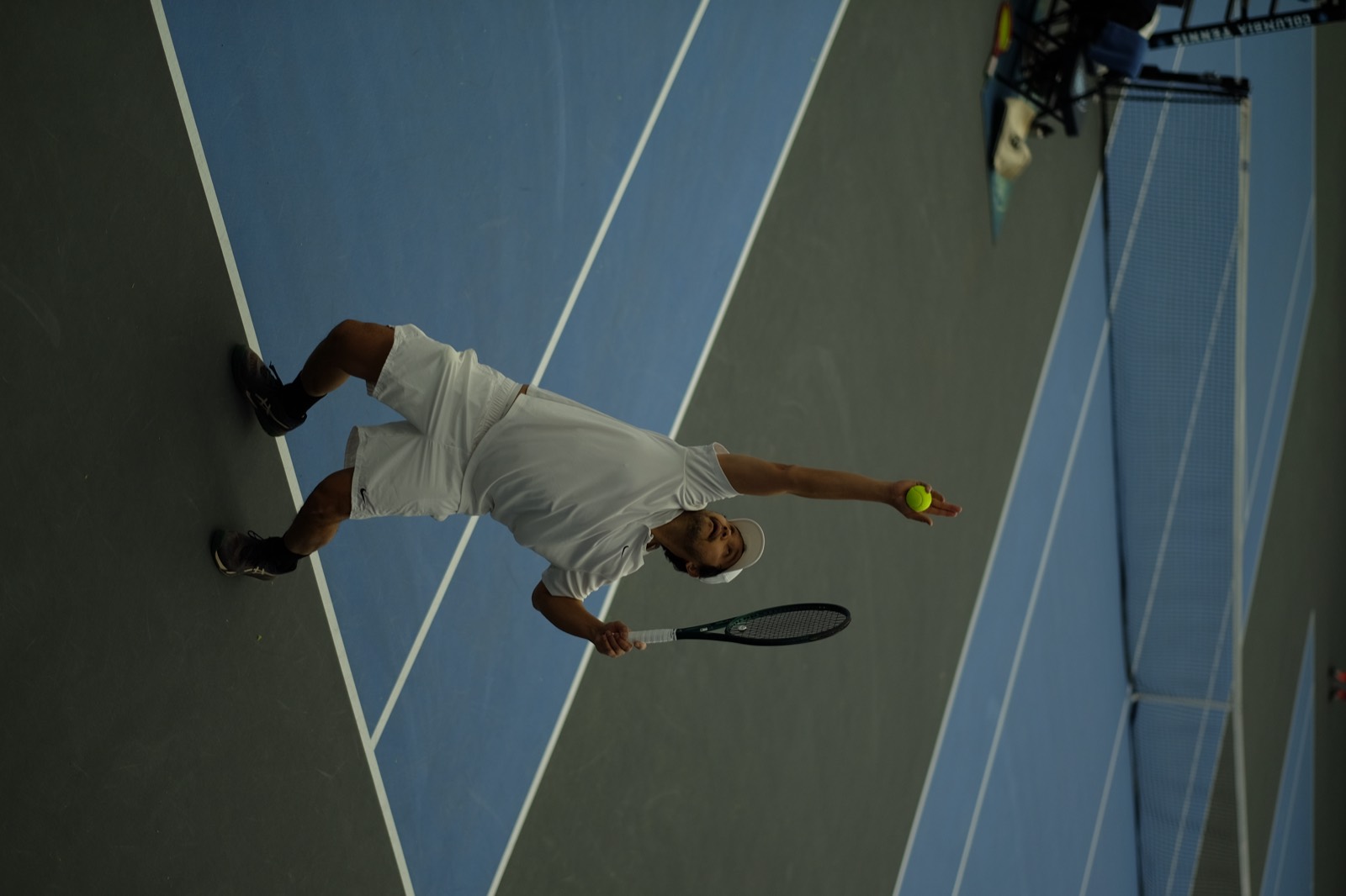 Tennis player serving on an indoor court